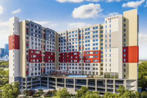 Diagonal elevation of Haven at Elgin, a 12‑story residential tower atop a 4‑story concrete parking podium. The reinforced concrete structure features floor‑to‑ceiling windows, recessed balconies with steel railings, and a bold red‑accented façade panel, illustrating engineered massing and modern urban form against a backdrop of downtown Houston.